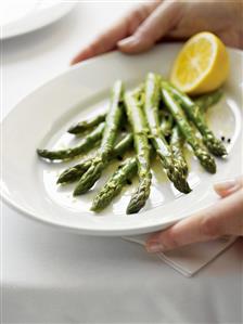 Hands Carrying a Plate of Lemon Asparagus