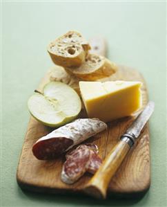 Apple, Cheese, Bread and Sausage on a Cutting Board