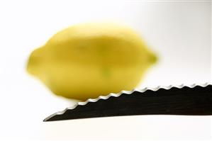 A knife point with a lemon in the background