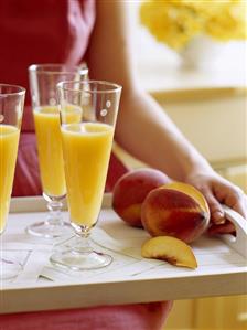 Woman holding a tray of peach juice and peaches