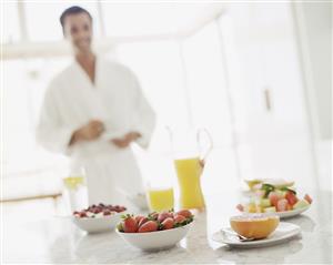 Man in bathrobe with fruit berries and orange juice