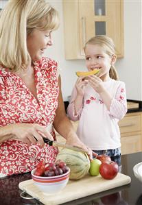 A grandmother giving her granddaughter some melon