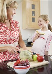 A grandmother giving her granddaughter some melon