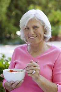 Woman outdoors with bowl of fruit smiling