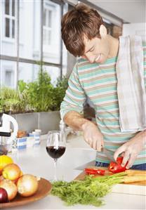 Man cutting red peppers in a kitchen