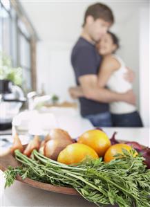 Bowl of fruits and vegetables with couple in background