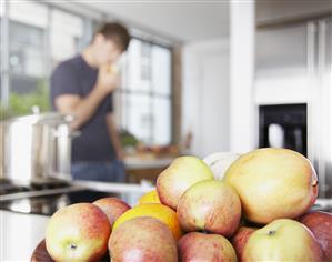 Bowl of mangos and nectarines with man in background eating