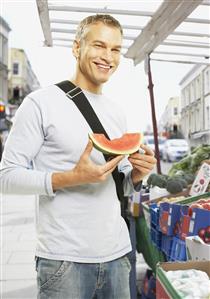 Man eating watermelon at market