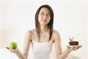 Woman deciding on piece of cake or apple