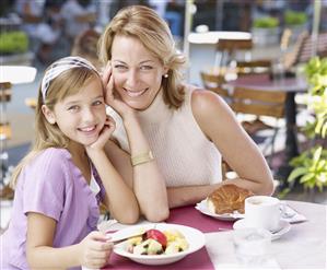 Woman and young girl on outdoor patio eating meal