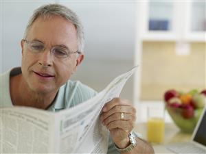 Man in kitchen reading newspaper