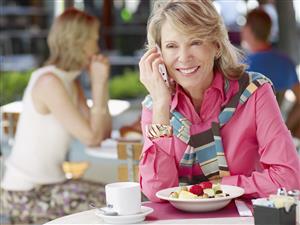 Woman on outdoor patio with her mobile phone and fruit bowl