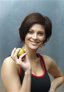 Woman standing in locker room holding apple