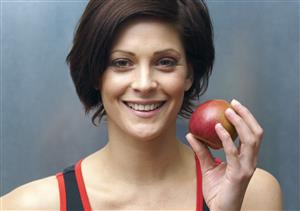 Woman standing in locker room holding apple