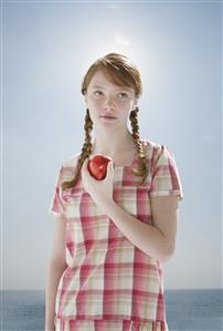 Young girl outdoors at a beach holding an apple