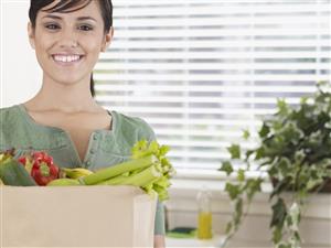 Woman in kitchen with grocery bag smiling