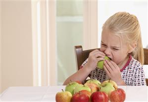 Young girl in kitchen eating an apple