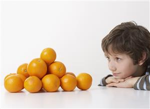 Young boy looking at pile of oranges