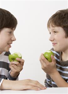 Two boys eating apples and smiling