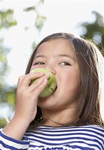 Young girl outdoors eating an apple