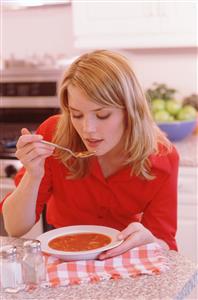 Mujer comiendo sopa.