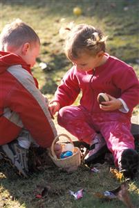 Niño y niña sentados en el jardin con huevos de chocolate. 