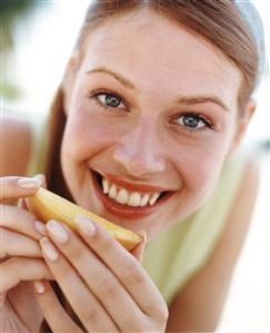 Mujer comiendo una tajada de melon  y sonriendo. Detalle.