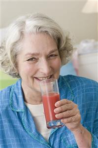 Mujer mayor tomandose un vaso de zumo.