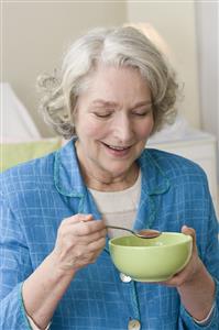 Mujer mayor comiendose un cuenco de sopa. Primer plano.