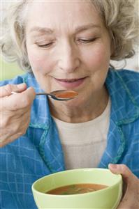 Mujer mayor comiendose un cuenco de sopa. Primer plano.