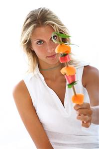 Mujer con una brocheta de frutas.