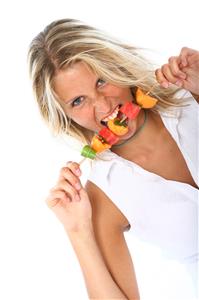 Mujer con una brocheta de frutas.