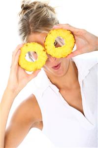 Mujer con dos rodajas de piña frente a los ojos.