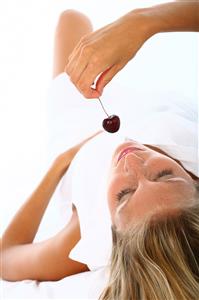 Mujer comiendo una cereza.