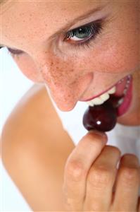 Mujer comiendo una cereza.  Detalle.