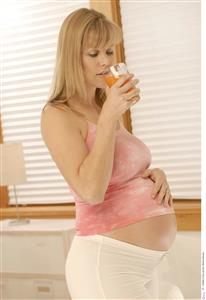 Mujer embarazada tomando un zumo de naranja.