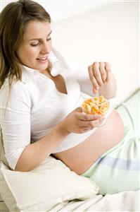 Mujer embarazada comiendo fruta.