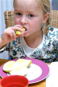 Niña comiendo una manzana. Primer plano.