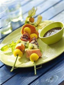 Brochetas de frutas con chocolate especiado. Receta disponible.