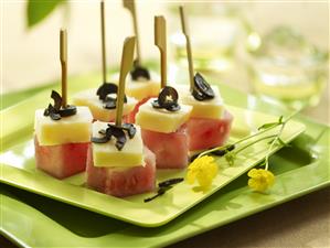 Pinchitos de sandia y queso con aceitunas negras. Receta disponible.
