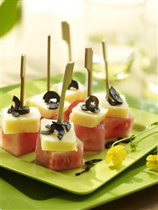 Pinchitos de sandia y queso con aceitunas negras. Receta disponible.
