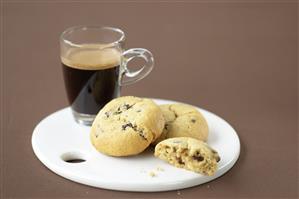 Cookies de chocolate con frutos secos y taza de cafe. Receta disponible.
