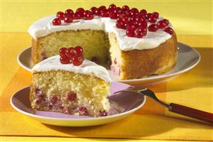 Pastel con pasas de Corinto adornado con nata gria y grosellas. Receta disponible.

