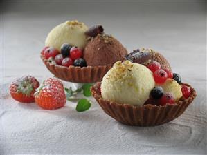 Helados de vainilla y chocolate con frutos rojos. Receta disponible.
