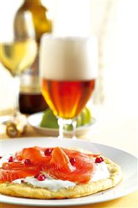 Pizza a la crema de leche agria con salmon, grosellas y copa de cerveza. Receta disponible.