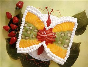 Tarta con fruta y nata montada, con forma de mariposa. Receta disponible.