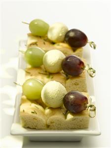 Mini brochetas de uvas y queso sobre pan. Receta disponible.