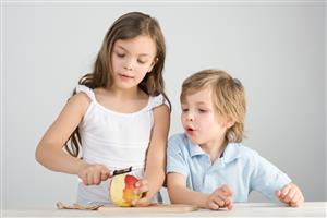 Boy watching girl peel apple