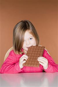 Girl biting a big bar of chocolate