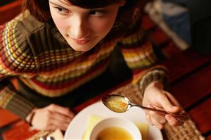 Young woman eating soup